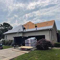 two roofers installing new gray shingles